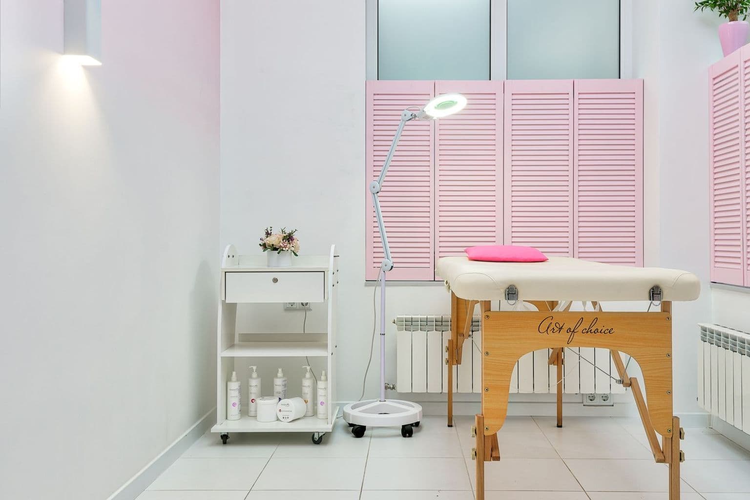 Sala de atendimento de uma clínica de estética, com maca, lupa e produtos