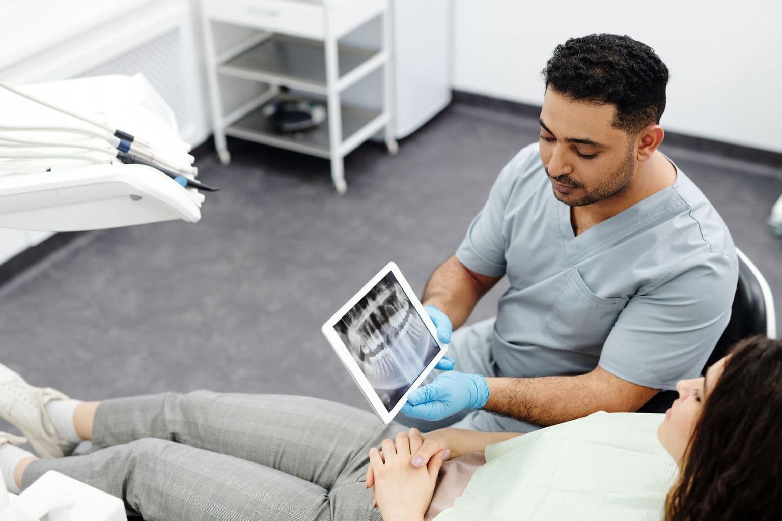Dentista mostrando uma radiografia no tablet para uma paciente